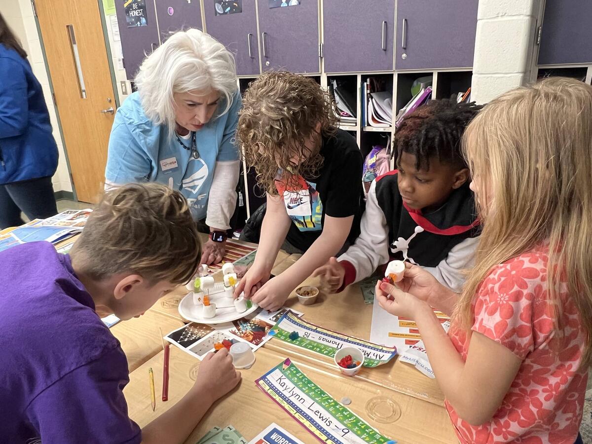 Woman engages in hands-on lesson with four students
